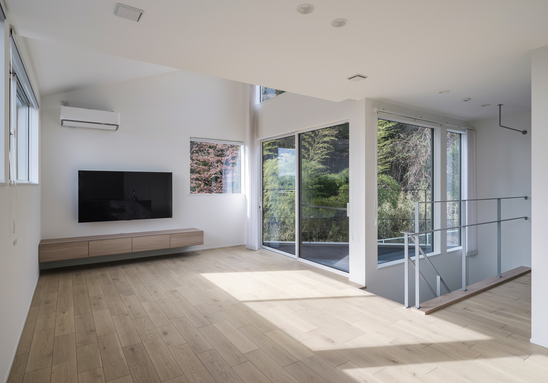 吹き抜けと大きな窓から光と緑を取り込む住宅のリビング